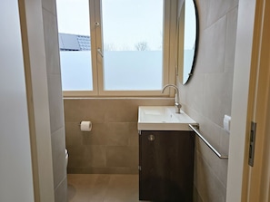 Ein Badezimmer mit Fenster, Waschbecken und Toilette.