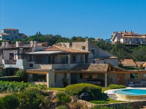 A villa with a swimming pool, a patio area, and a view of surrounding buildings. - Holiday Home With 1 Bedroom (Arzachena)