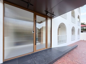 Een modern gebouw met grote schuifdeuren, een plat dak en een met baksteen bestraat pad.