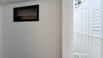 Una pared blanca con un ventanal de marco negro y barandilla de balcón blanca.