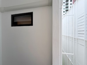 Una pared blanca con un ventanal de marco negro y barandilla de balcón blanca.