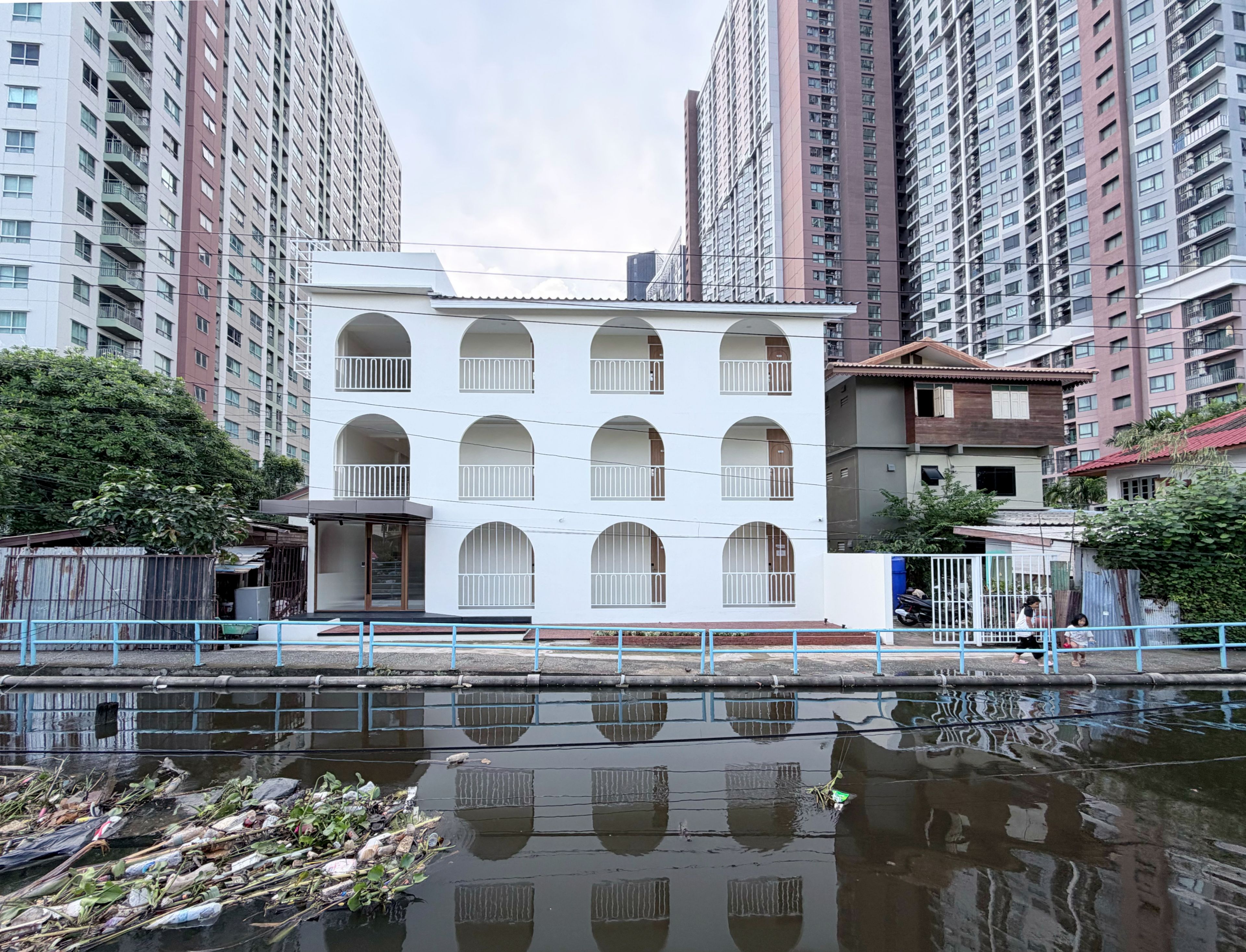 Un edificio residencial de varios pisos con fachada blanca, ventanas en arco y balcones.