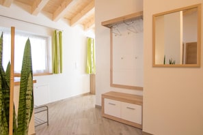 A room with a wooden ceiling, a window with curtains, a mirror, and a wooden cabinet.