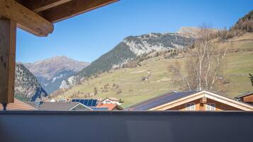 A mountain view from a wooden balcony with solar panels on the roof.