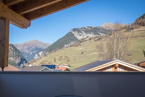 Blick auf Berge von einem Holzbalkon mit Solaranlage auf dem Dach.