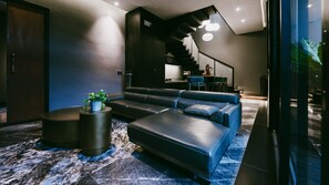 A modern living room with a sectional sofa, a coffee table, and a potted plant. - Moonstone Luxury Villa (Badung)