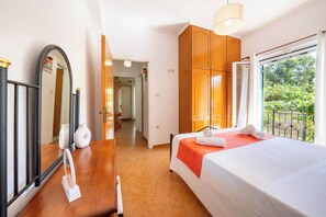 Une chambre d’hôtel avec un lit, une commode, un miroir et une fenêtre donnant sur un paysage verdoyant.