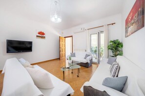A modern living room with a flat-screen TV, a glass coffee table, and a sofa. - Kallithea House Corfu - Courtyard & Beach Days (Gouvia)