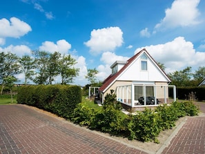 Eingeschossiges Haus mit rotem Dach, einer überdachten Veranda und einer Auffahrt aus Ziegelsteinen.