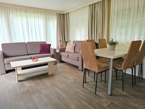 A modern living room with a sofa, a coffee table, and a dining table with chairs. - Holiday Home With 1 Bedroom (Oostkapelle)