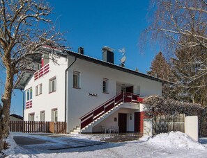 A two-story building with a white exterior and red accents, a staircase leading to the entrance, and a clear blue sky in the background. - Apartment in Aufhofen With Swimming Pool (Brunico)