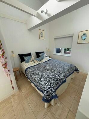 Un dormitorio con cama, ventana y lámpara en el techo.