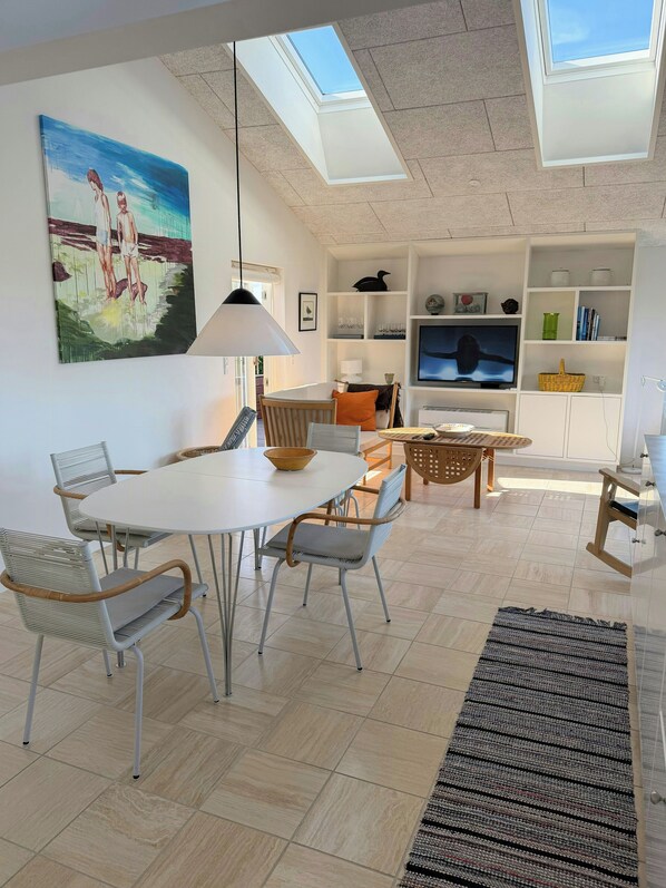 Una sala de estar moderna con comedor, televisor y tragaluz.