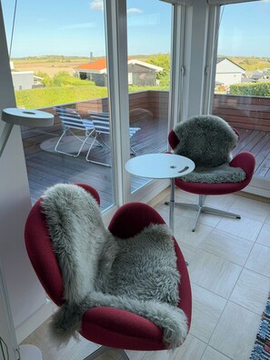 A room with a large window, a small round table, and two red chairs with fur trim. - Summer house with terrace towards Kerteminde Bay (Kerteminde)