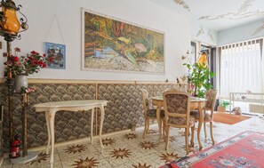 Et spiseområde med et bord, stole, en dekorativ lampe, et billede og en potteplante.