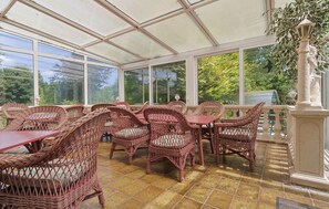 En overdækket terrasse med fletningsmøbler og store vinduer.