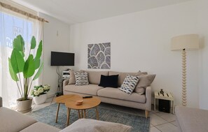 A living room with a sofa, a coffee table, a TV, a lamp, and a large plant. - Watersnip - Enjoying the water (Lemmer)