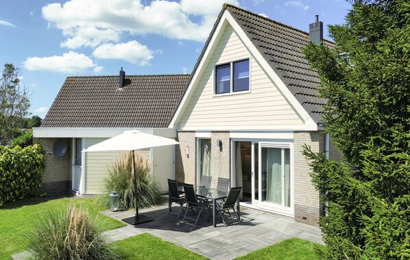 A two-story house with a patio area featuring a table and chairs, a sliding glass door, and a covered outdoor seating area. - Watersnip - Enjoying the water (Lemmer)