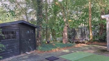 A wooden shed, a trampoline, and a green artificial turf area in a backyard.