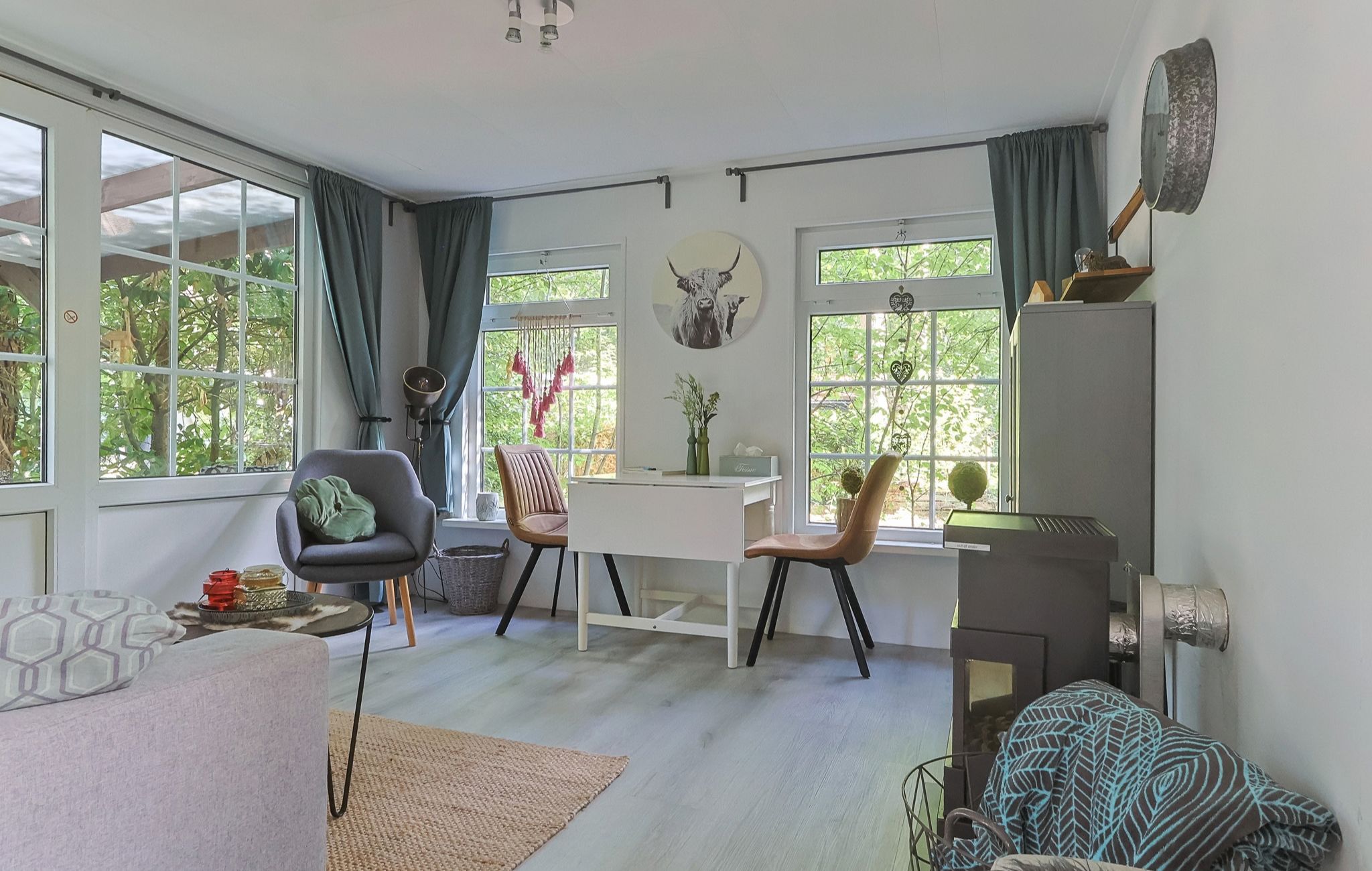 A modern living space with a dining area, two chairs, a table, and large windows with curtains.