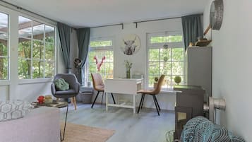 A modern living space with a dining area, two chairs, a table, and large windows with curtains.