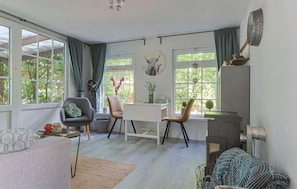 Un espacio de estar moderno con comedor, dos sillas, una mesa y ventanas grandes con cortinas.