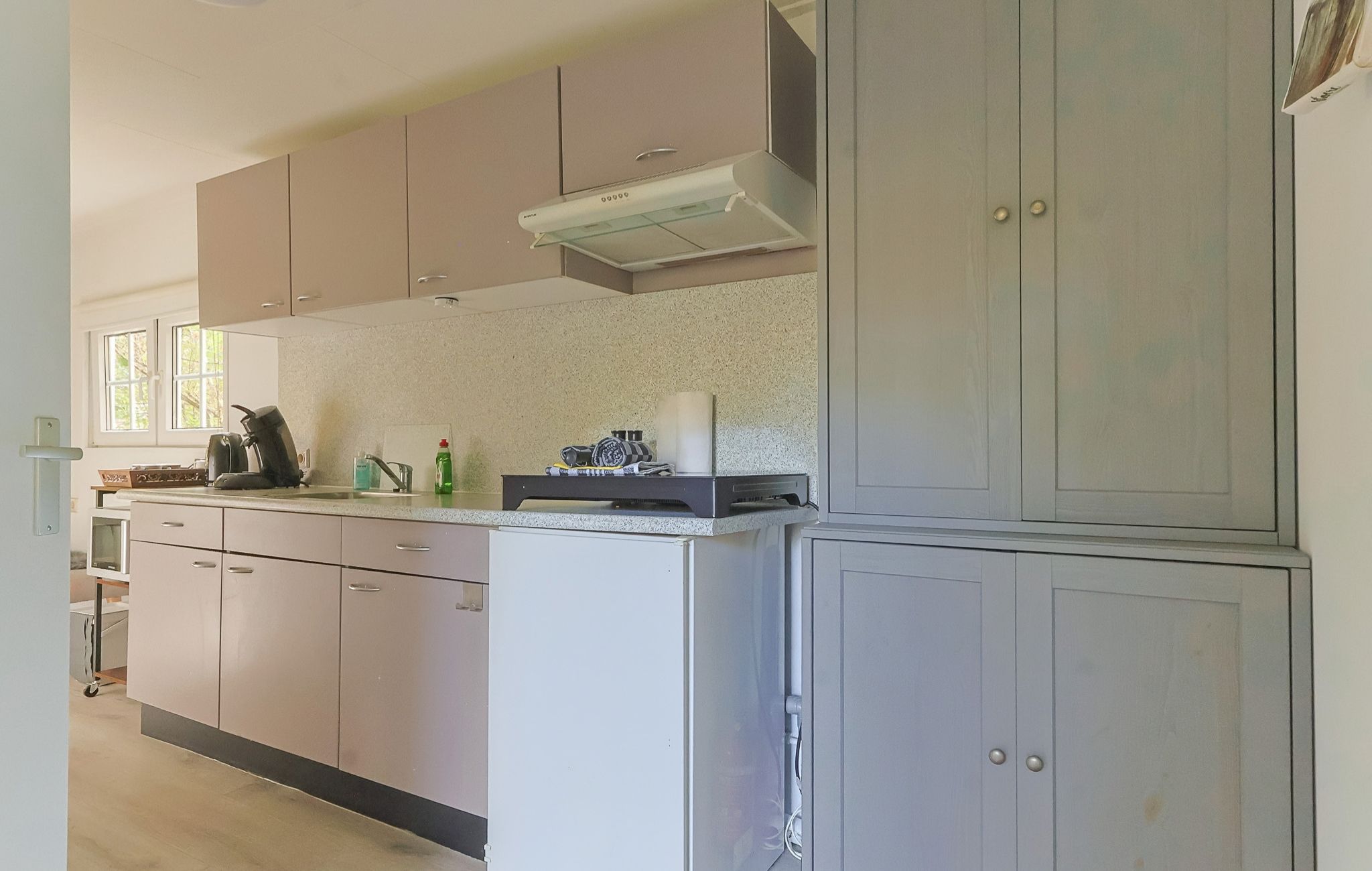 Een keuken met kasten, een aanrecht en een afzuigkap.