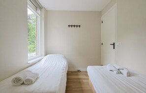 A hotel room with two beds, a window, a door, and a wall-mounted towel rack. - De Tilgrup in Oude Willem (Oude Willem)