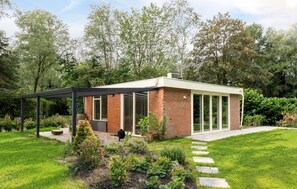 A modern house with a glass conservatory, brick exterior, and a garden with stepping stones. - De Tilgrup in Oude Willem (Oude Willem)