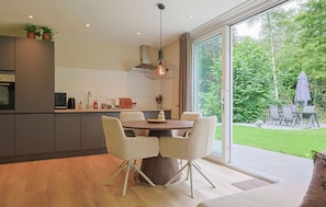 Eine moderne Küche mit Essbereich, großen Fenstern und Blick auf den Garten.