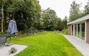 A well-maintained garden with a lawn, a small shed, and a patio area with a table and chairs. - De Tilgrup in Oude Willem (Oude Willem)