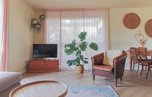 A living room with a television, a leather armchair, a dining table with chairs, and a large potted plant. - Waterfront Villa Strikel 18 Terherne (Terherne)