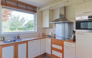 A modern kitchen with a stainless steel range hood, a built-in oven, and a window with a view of the outside. - Waterfront Villa Strikel 18 Terherne (Terherne)