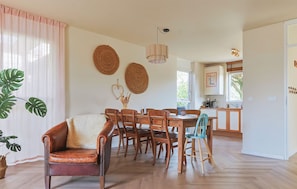 A dining area with a wooden table and chairs, a leather armchair, and a hanging light fixture. - Waterfront Villa Strikel 18 Terherne (Terherne)