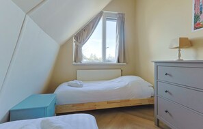 A bedroom with a sloped ceiling, a single bed, a dresser, and a window with curtains. - Waterfront Villa Strikel 18 Terherne (Terherne)