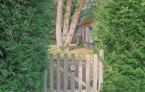 A wooden gate with a birdhouse, surrounded by dense green foliage. - Tiny house in the forest near Veluwezoom (Hattemerbroek)