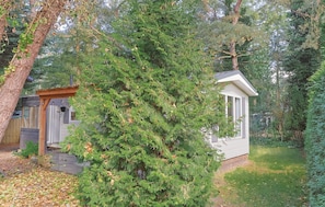 A small wooden structure with a porch, surrounded by dense green foliage. - Tiny house in the forest near Veluwezoom (Hattemerbroek)