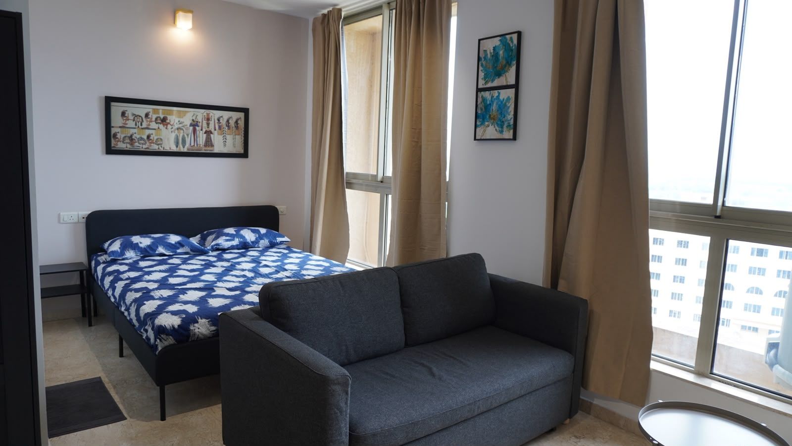 Una habitación con una cama, un sofá, una mesita y una ventana con cortinas.