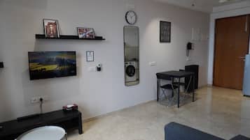Quarto com televisão de tela plana, máquina de lavar, relógio e porta.