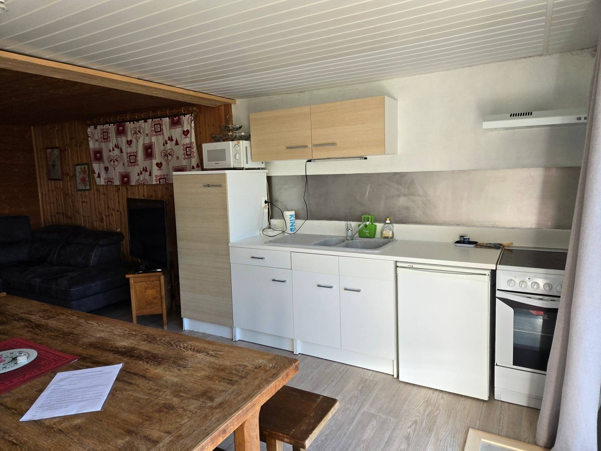 Une cuisine compacte avec des meubles blancs, un four à micro-ondes, une cuisinière et un évier.
