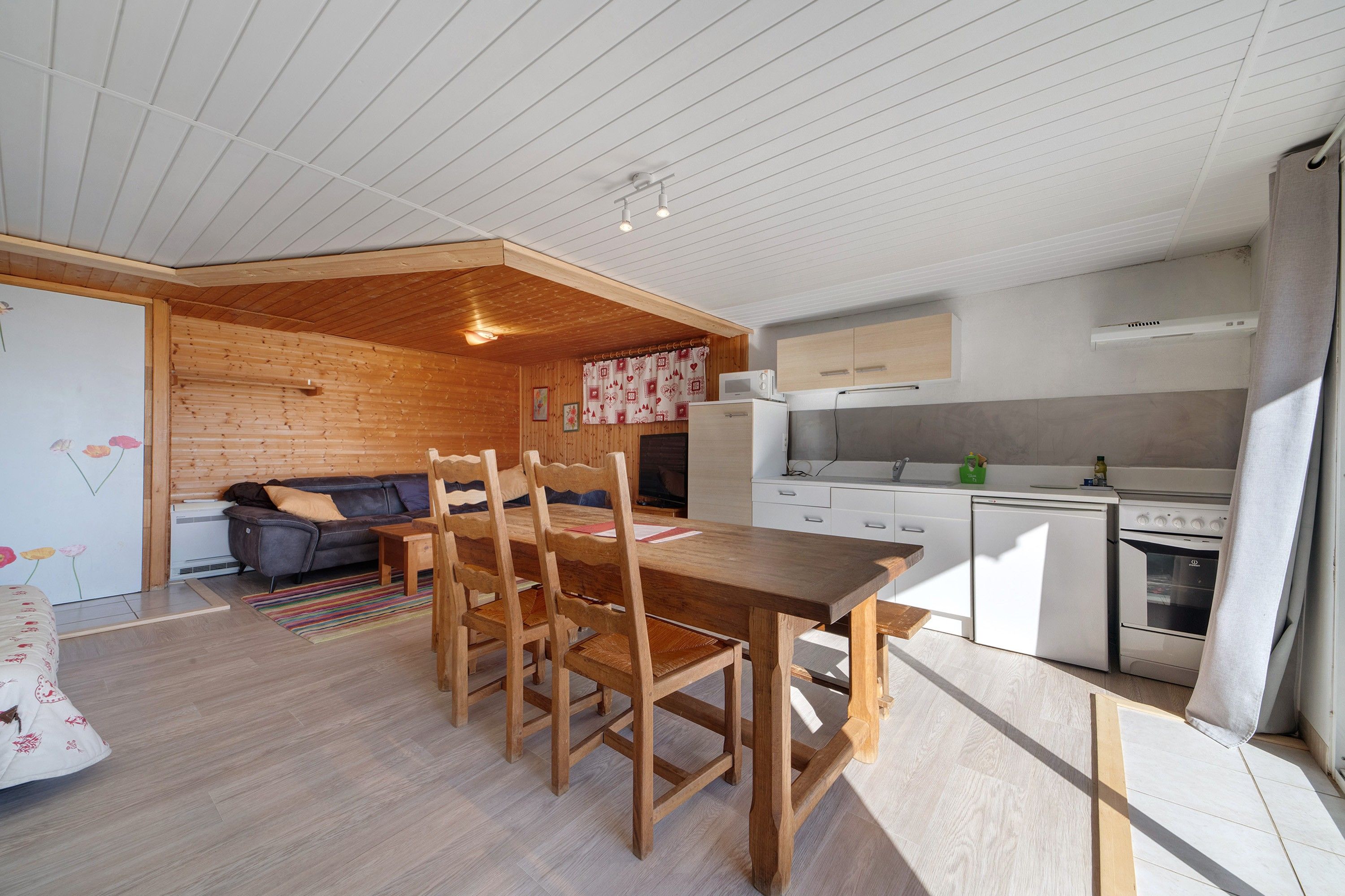 A compact living space with a dining area, kitchenette, and a sofa.