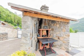 A stone-built outdoor kitchen with a chimney, a table, and a bag of charcoal. - Bellevue Vacation Rental with Pool (3-star) (Agos-Vidalos)