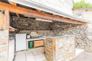 A stone-walled outdoor kitchen area with a built-in sink and wooden beams overhead. - Bellevue Vacation Rental with Pool (3-star) (Agos-Vidalos)
