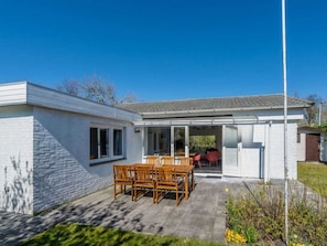 A house with a patio, a dining area with wooden furniture, and a covered outdoor space. - Holiday Home in Renesse With Swimming Pool (Renesse)