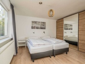A modern bedroom with a double bed, a large mirror, and artwork on the wall. - Holiday Home in Renesse With Swimming Pool (Renesse)