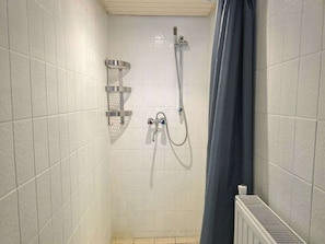 A shower area with a handheld showerhead, a wall-mounted faucet, and a corner shelf. - Holiday Home With 2 Bedrooms (Oostkapelle)