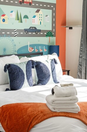 Una habitación de hotel con cama, almohadas, una colcha y un mural en la pared.