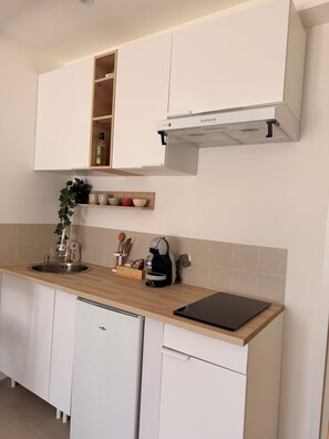 Eine moderne Küche mit weißen Schränken, einer Holzarbeitsplatte, einem Einbauofen und einer Kaffeemaschine.