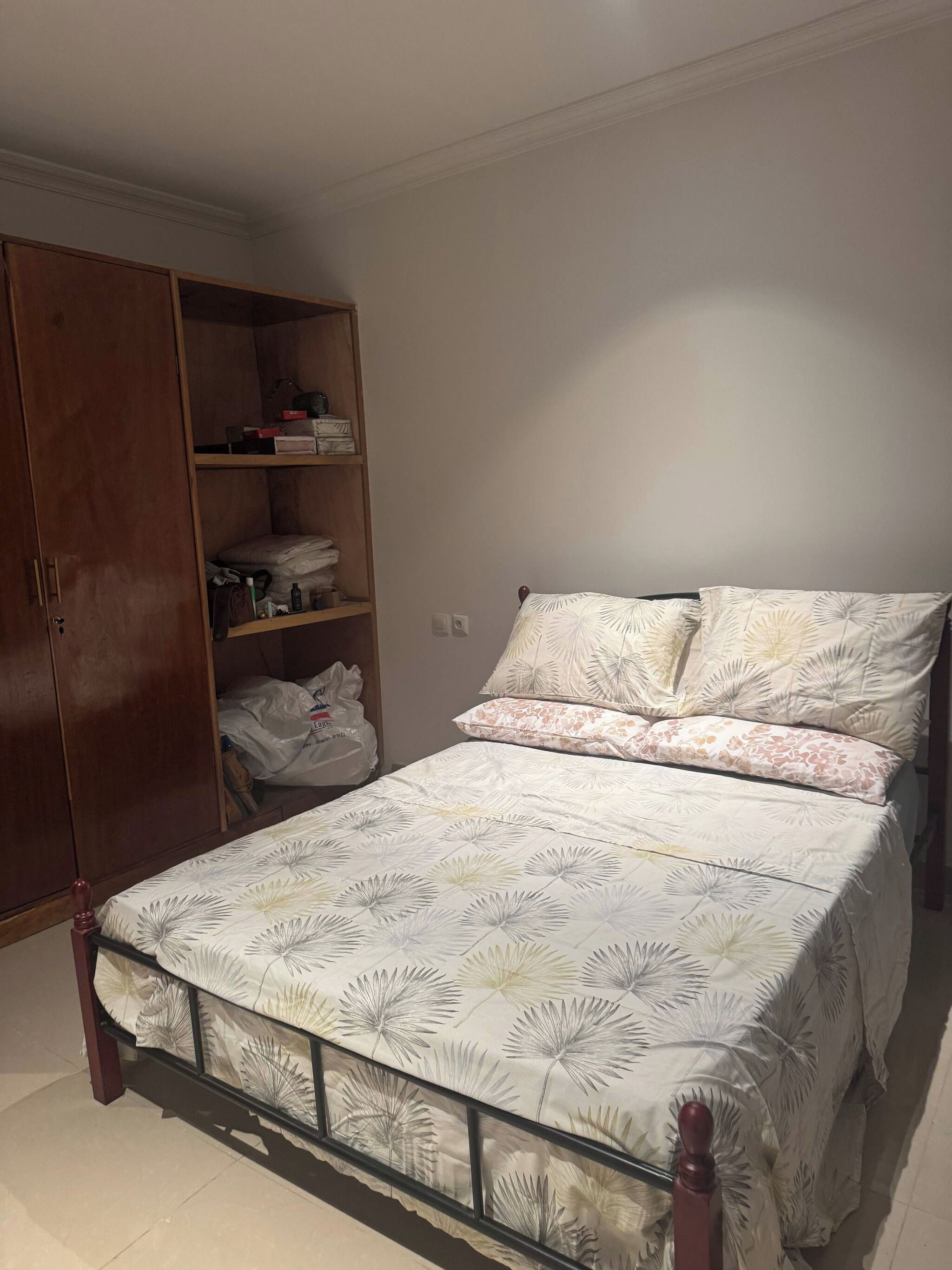 Un dormitorio con cama, armario y estantería.