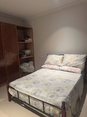 A bedroom with a bed, a wardrobe, and a shelf unit.